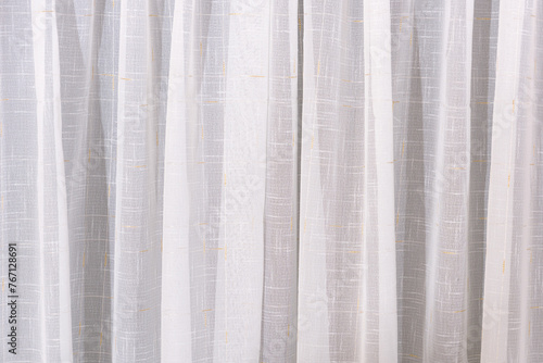 The white curtain hangs in folds. The waves of the fabric are transparent and clean.