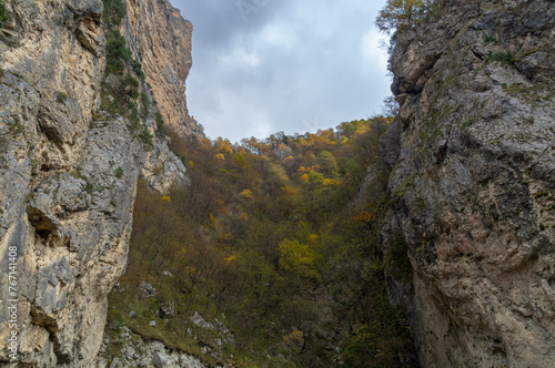 The outlines of the mountain range in autumn. Colorful foliage of trees in autumn in the mountains. A mountain gorge high in the mountains. A landscape in a mountainous area.