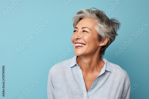 smiling senior woman with grey hair and blue shirt on blue background