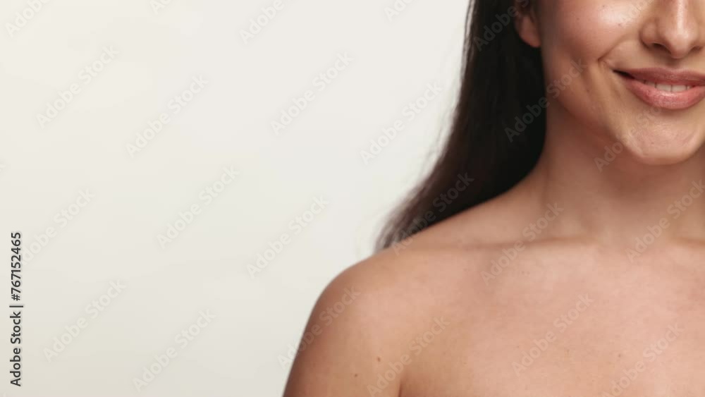 A close-up image capturing the beautiful smile of an unrecognizable woman with bare shoulders against a neutral background. A close-up image capturing the beautiful smile of an unrecognizable woman with bare shoulders against a neutral background.