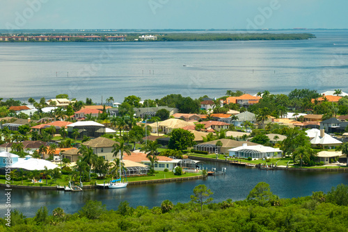 Aerial view of rural private houses in remote suburbs located on sea coast near Florida wildlife wetlands with green vegetation on gulf bay shore. Living close to nature in tropical region concept