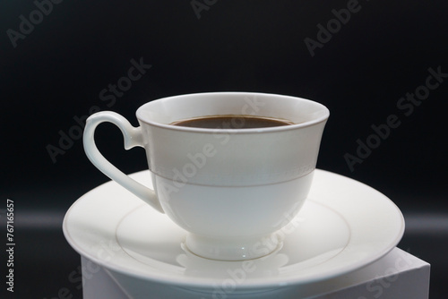 black coffee poured into a porcelain coffee pair on a black background