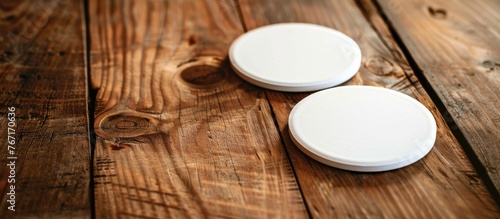 Two empty white beer coasters are displayed on a rustic wooden table background. This setup serves as a demonstration of responsive design. photo