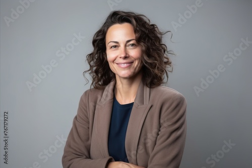 Portrait of a happy mature business woman smiling at the camera, over grey background