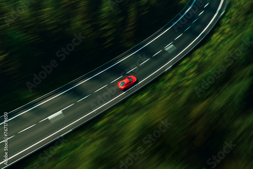 Dynamic Aerial View of a Vibrant Red Car Speeding Along a Serpentine Forest Road