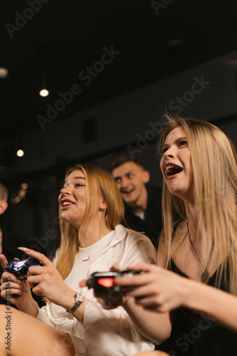 Blonde ladies engage in playing video games on console in club. Women captivate attention of avid gamer with exciting competition