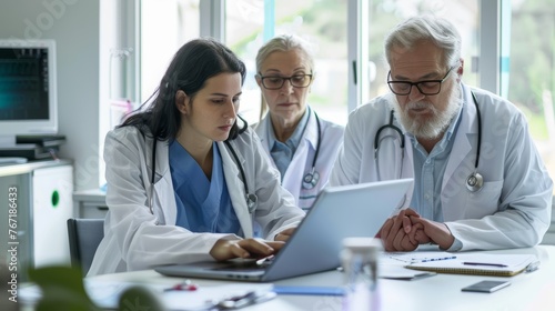 Diverse group of medical specialists reviewing electronic health records on laptop photo