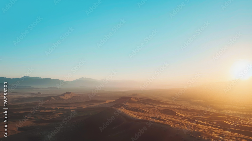 Sunrise over desert dunes with distant mountains