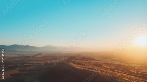 Sunrise over desert dunes with distant mountains