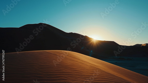 Sunrise cresting over sand dunes in desert