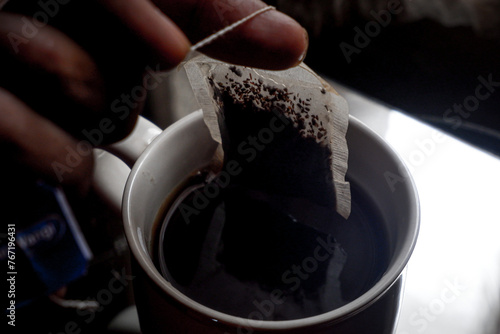 Putting tea bag into glass cup full of hot water  photo