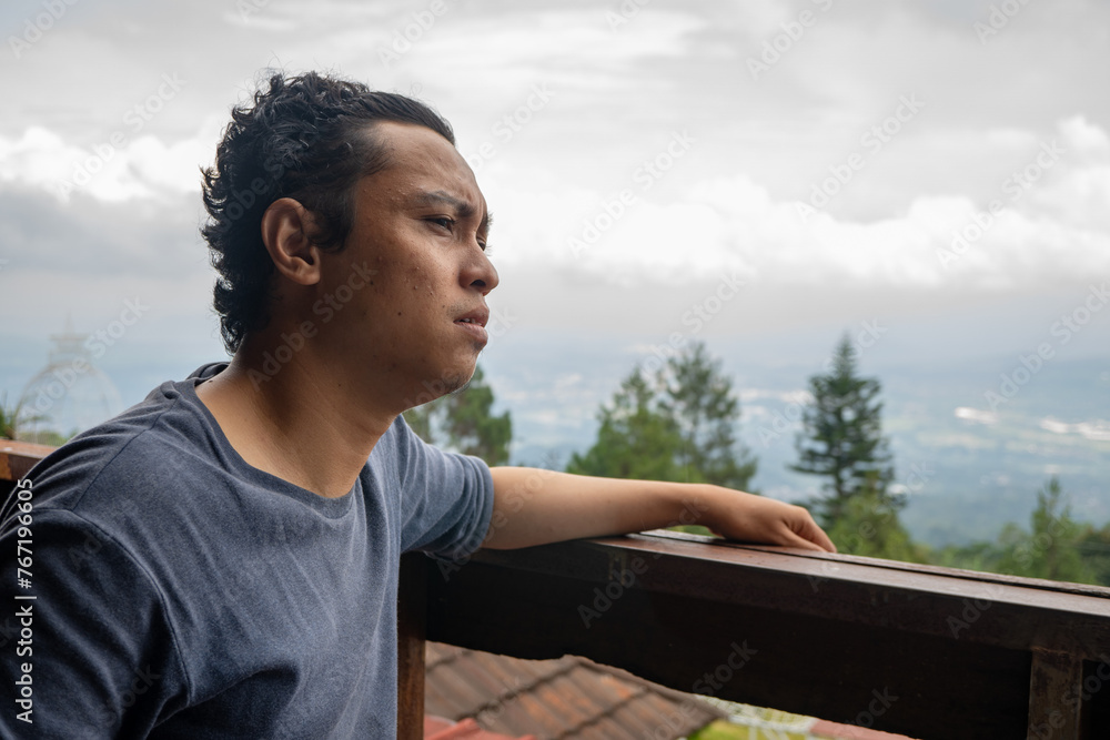 Fototapeta premium Man sitting near fence and looking the landscape mountain. The photo is suitable to use for calm enjoyed activity, leisure activity and park background.