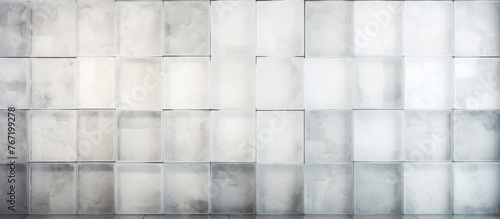 A grey wall with a pattern of rectangular squares made of wood flooring. The tints and shades create a symmetrical pattern. Glass font adds transparency