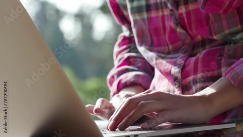 A beautiful asian woman working and typing on laptop computer while sitting on balcony with mountains and green nature background