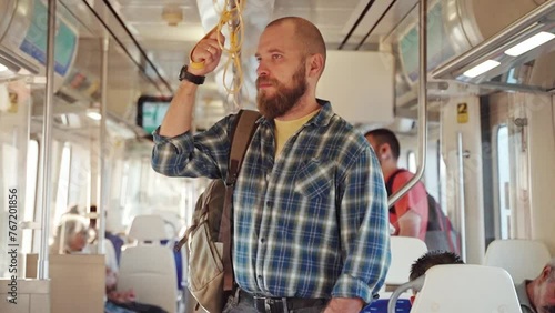 City dweller with a backpack using metro train car. An adult heading to work, using a cellphone on public transport. Urban life in the morning as a citizen relies on the subway