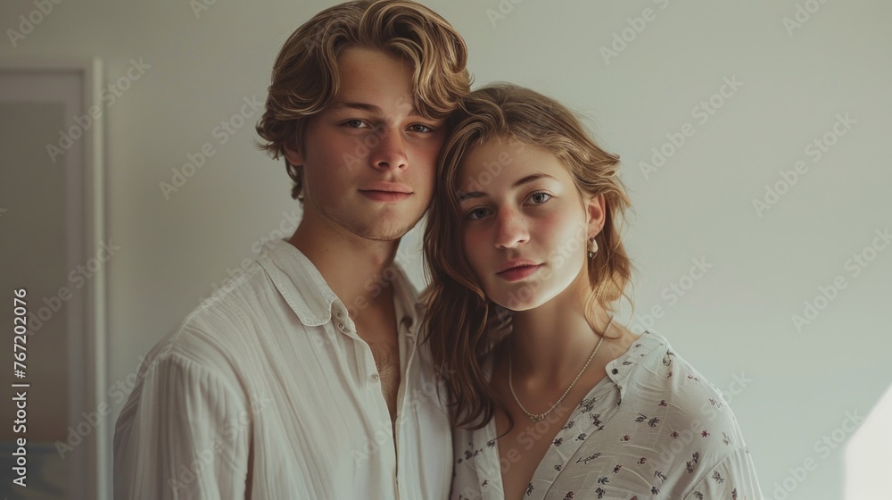 Young couple posing for a portrait with a soft natural light wearing white blouses and sharing a gentle affectionate moment. Young couple posing for a portrait with a soft natural light wearing white blouses and sharing a gentle affectionate moment.