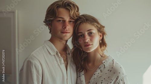 Young couple posing for a portrait with a soft natural light wearing white blouses and sharing a gentle affectionate moment.