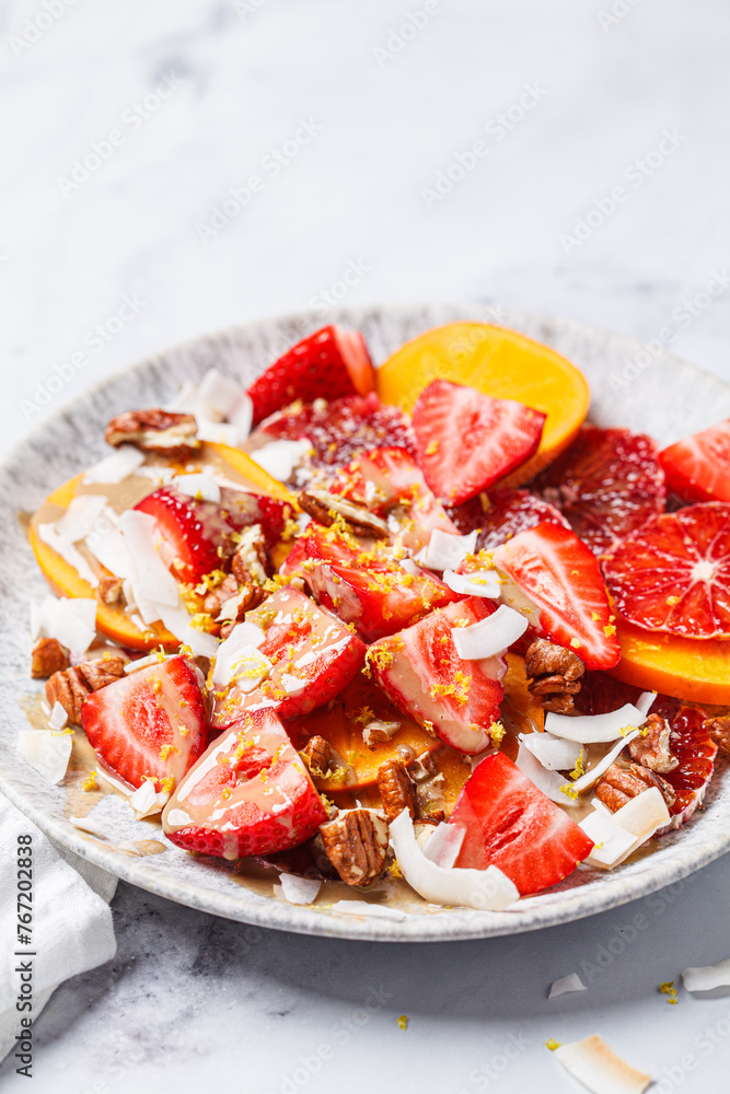 Fruit salad with persimmon, orange, strawberries, coconut chips and lemon zest.