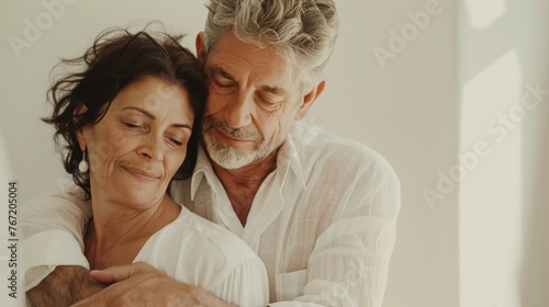 An elderly couple sharing a tender embrace their eyes closed in contentment set against a soft-focus warm-toned background.