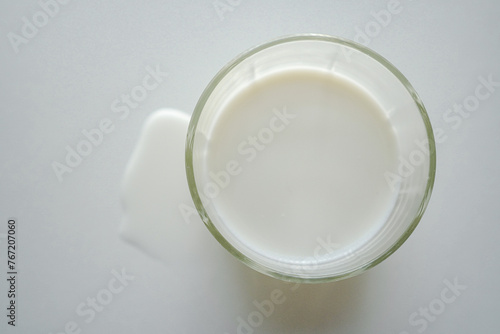 上から見たグラスに入った牛乳とこぼれた牛乳 白背景