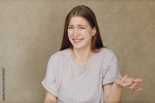 Portrait of young caucasian surprised skeptical woman looking at camera against beige background
