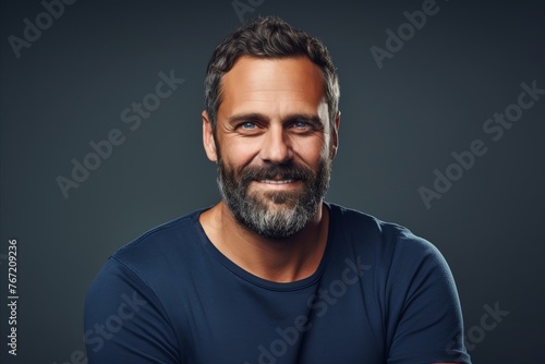 Portrait of a handsome bearded man in a blue t-shirt over dark background.
