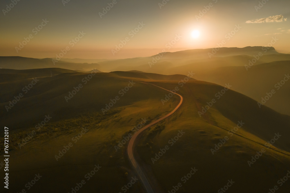 Road in the green hills at foggy sunrise. Gil-Su valley in North Caucasus, Russia.