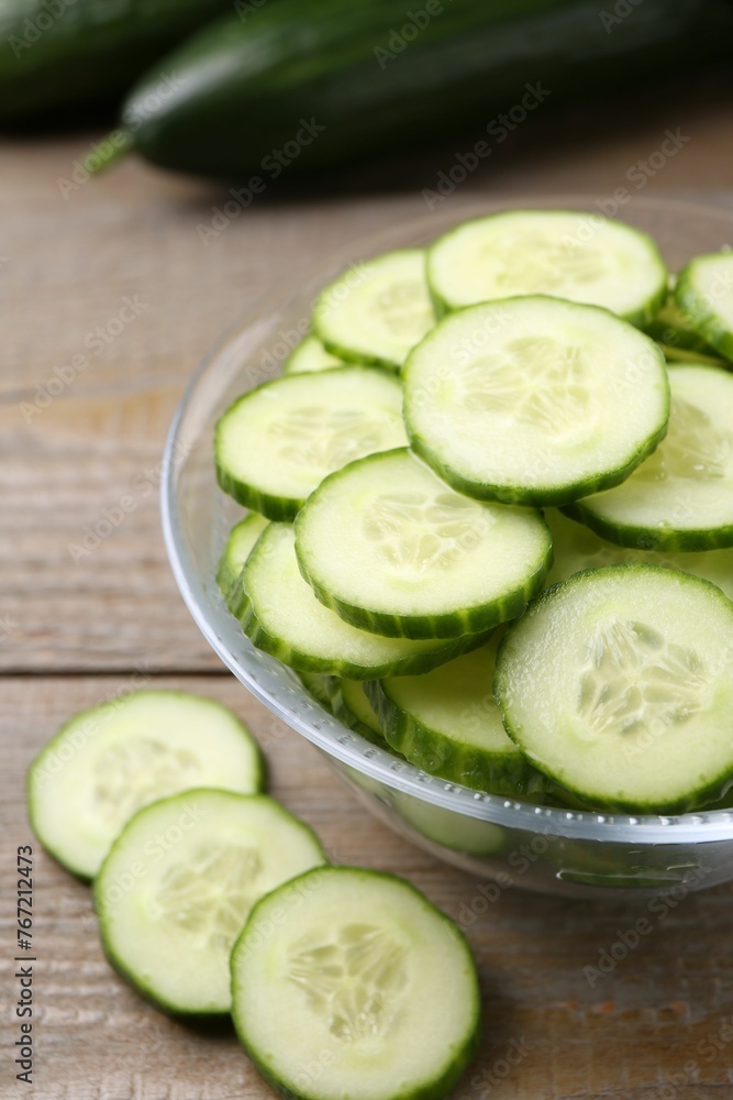 Cut cucumber in glass bowl on wooden table, closeup Cut cucumber in glass bowl on wooden table, closeup