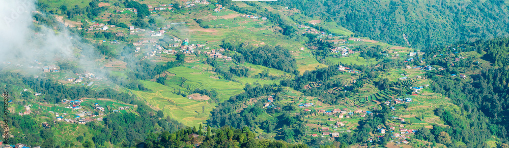 Obraz premium Aerial view of some Nepalese villages surrounded by nature and rice fields in the valleys at the foot of the Himalayan mountain range, seen from Nagarkot. Nepal