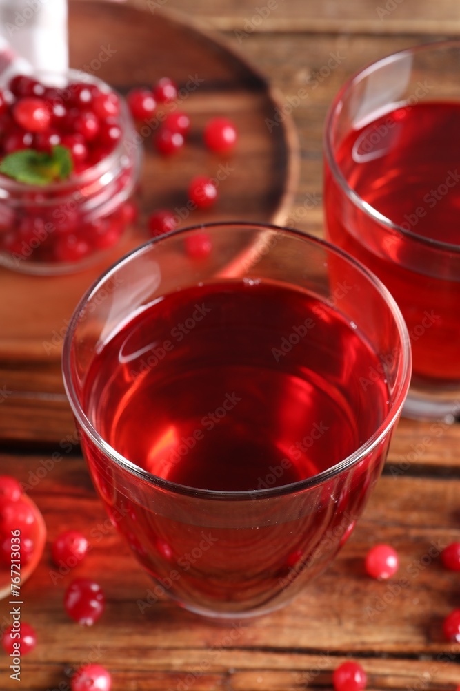 Tasty cranberry juice in glasses and fresh berries on wooden table, closeup Tasty cranberry juice in glasses and fresh berries on wooden table, closeup