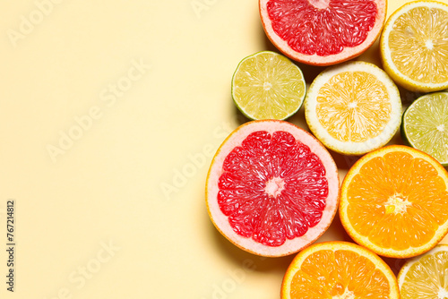 Different cut citrus fruits on beige table  flat lay. Space for text