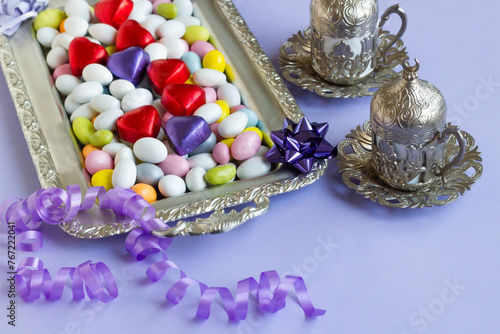Colorful almond candies were designed on a silver tray with heart-shaped wrapped chocolates and coffee