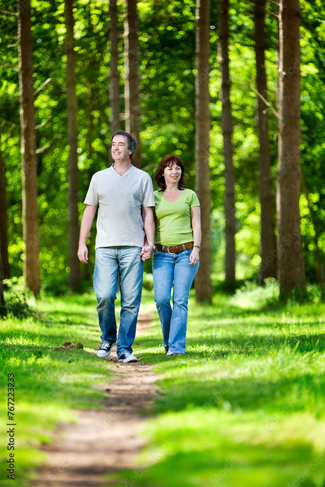 Life begins at 40. A mature couple enjoying time together as they enjoy the warm summer weather in a sunny woodland park. Life begins at 40. A mature couple enjoying time together as they enjoy the warm summer weather in a sunny woodland park.