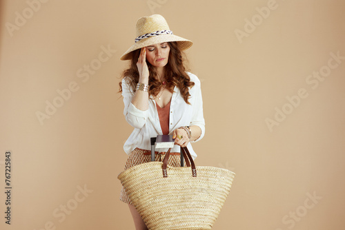 pensive stylish woman in blouse and shorts against beige