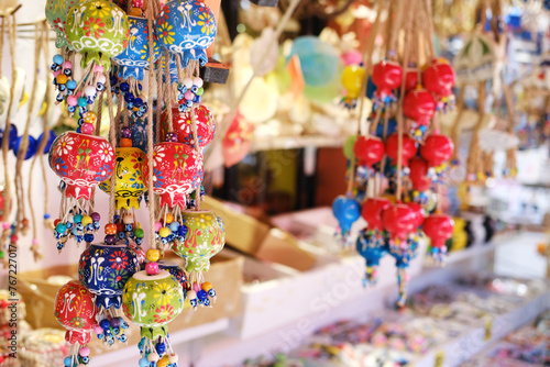 Hand-Painted Ceramic Bell Ornaments with Beads. Vibrantly colored, hand-painted ceramic bell ornaments and beads hanging in a Turkish coastal town shop.