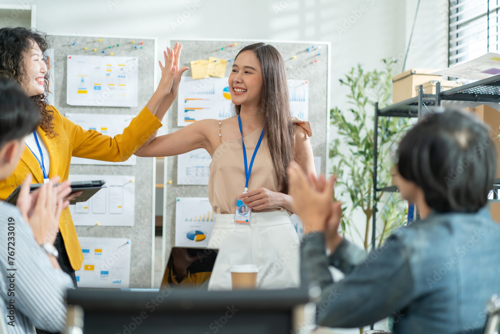 Group of asian businesspeople are keeping arms raised hi five and expressing joyful while standing for her work achievement in front of her coworkers.achieving goals.high five,closing a deal,success Group of asian businesspeople are keeping arms raised hi five and expressing joyful while standing for her work achievement in front of her coworkers.achieving goals.high five,closing a deal,success