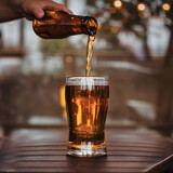 Pouring Golden Beer into a Glass on a Cozy Bar Table