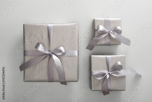 Set of monochrome silver gift boxes with gray ribbons on light background.