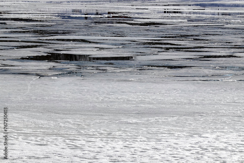 Early spring, many dangerous white melting ice floes floating in the river water near coastline