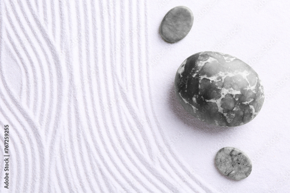 Fototapeta premium Zen garden stones on white sand with pattern, flat lay