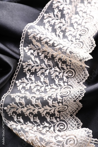 Beautiful white lace on black fabric, top view