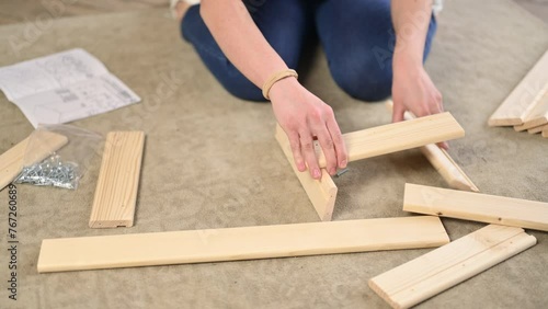 Close-up of assembling a shelf or cabinet according to instructions. Young woman trying to assemble a rack