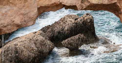 A view of a rock in the sea through a blurred stone arch. Seascape banner © Armands photography