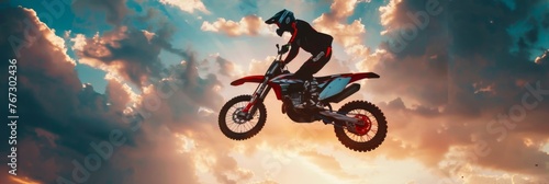 Extreme motocross where the rider drives off a dirt ramp and soars through the air against a spectacular sky