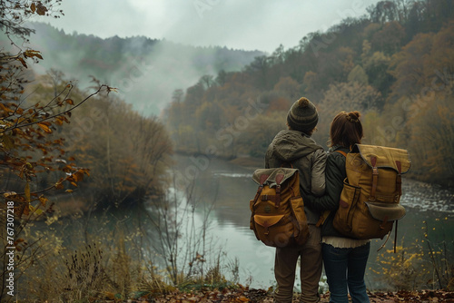 Couple with backpacks enjoying a misty river view in autumn. Hiking and relationship concept. Design for travel content, banner, and couples retreat promotion.