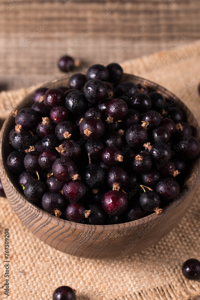 Black currant in a bowl on wooden background. Organic berries. Black currant in a bowl on wooden background. Organic berries.