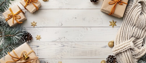 Composition for Christmas, including gifts, fir tree branches, and a knitted blanket on a white wooden background. Displayed in a flat lay style with a top view and space for text.