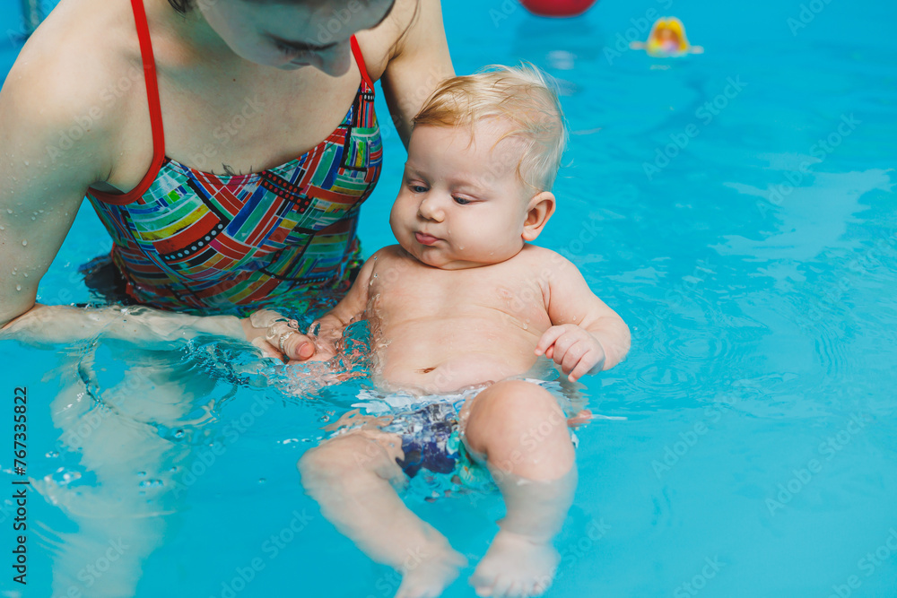 A 6monthold baby learns to swim with a coach in the pool. Swimming