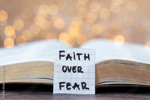 Photos Faith over fear, handwritten quote and open holy bible book with bokeh light background