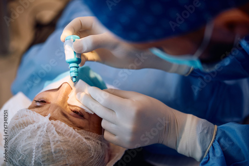 Mature woman getting anesthetic eye drops before laser surgery at ophthalmology clinic. photo